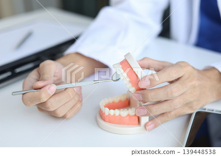 Dentist using a dental model to demonstrate oral health. 139448538