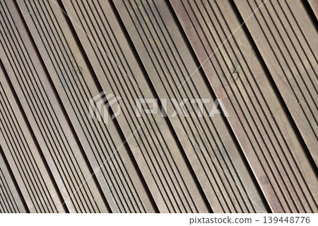 Wooden deck flooring with parallel grooves and lines, showcasing a diagonal arrangement of planks in natural wood tones and textures Wooden deck flooring with parallel grooves and lines, showcasing a diagonal arrangement of planks in natural wood tones and textures 139448776