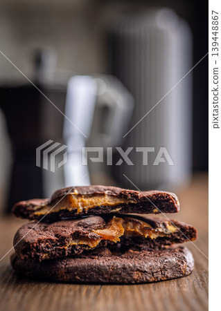Warm Chocolate Cookies Filled With Gooey Caramel Served With Coffee On Wooden Table Warm Chocolate Cookies Filled With Gooey Caramel Served With Coffee On Wooden Table 139448867