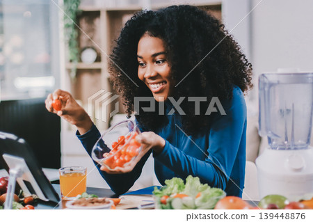 Young nutritionist showing bell peppers during an online video call consulting about healthy eating, sitting at home at a table with vegetables, laptop and measuring tape Young nutritionist showing bell peppers during an online video call consulting about healthy eating, sitting at home at a table with vegetables, laptop and measuring tape 139448876