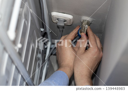 A worker installing or repairing a plumbing valve, likely for a washing machine A worker installing or repairing a plumbing valve, likely for a washing machine 139448983