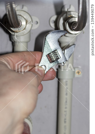 Plumber working on the plumbing drain pipes under a sink 139449079