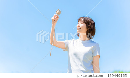 Woman cooling off with a handheld fan - summer heatstroke prevention Woman cooling off with a handheld fan - summer heatstroke prevention 139449165