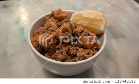 Crispy fried squid in a white bowl with a slice of lemon Crispy fried squid in a white bowl with a slice of lemon 139449188