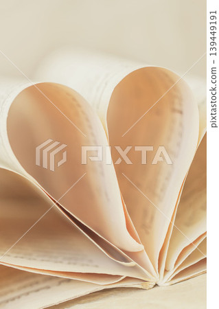 Blurred open book with music sheet pages in heart shape, soft light. Music sheet pages folded into heart shape with paper curves. Concept of music, romance, melody, gentle memories, romantic mood Blurred open book with music sheet pages in heart shape, soft light. Music sheet pages folded into heart shape with paper curves. Concept of music, romance, melody, gentle memories, romantic mood 139449191