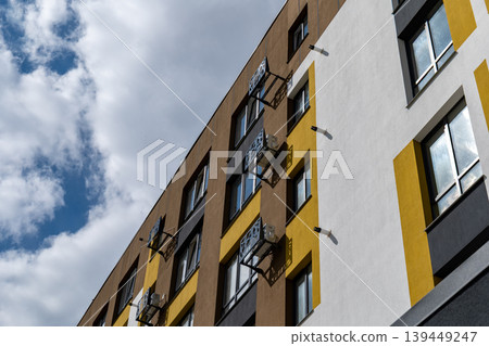 New multi storey building features air conditioning units on the exterior under a blue sky with clouds on a sunny day New multi storey building features air conditioning units on the exterior under a blue sky with clouds on a sunny day 139449247