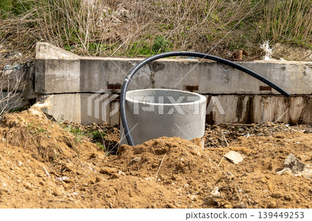 A sewer manhole is installed in an open area with dirt and a pipe nearby during daylight. Surrounding land shows signs of construction work A sewer manhole is installed in an open area with dirt and a pipe nearby during daylight. Surrounding land shows signs of construction work 139449253