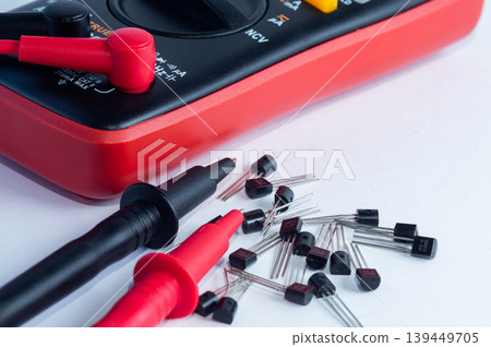 Multimeter with measurement probes and transistors on a white background Multimeter with measurement probes and transistors on a white background 139449705
