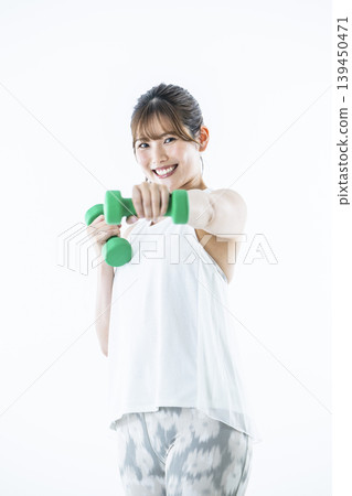年輕女子運動服看著相機啞鈴拳 年輕女子運動服看著相機啞鈴拳 139450471