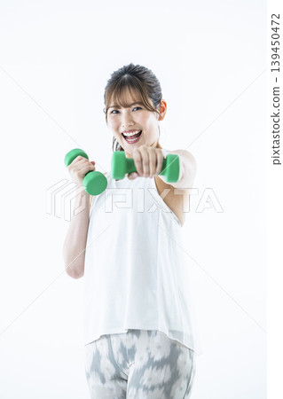 年輕女子運動服看著相機啞鈴拳 年輕女子運動服看著相機啞鈴拳 139450472