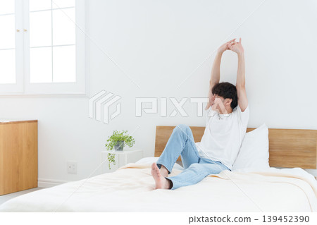 A man stretching in bed 139452390