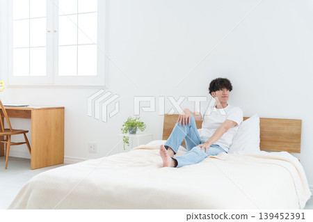 A man stretching in bed A man stretching in bed 139452391