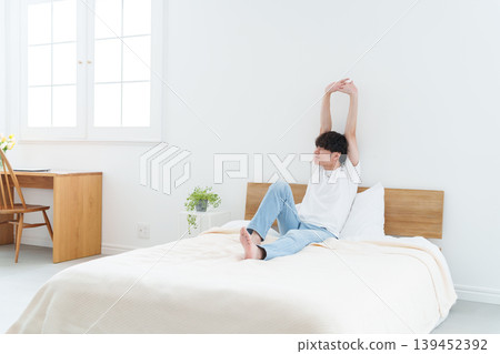 A man stretching in bed A man stretching in bed 139452392