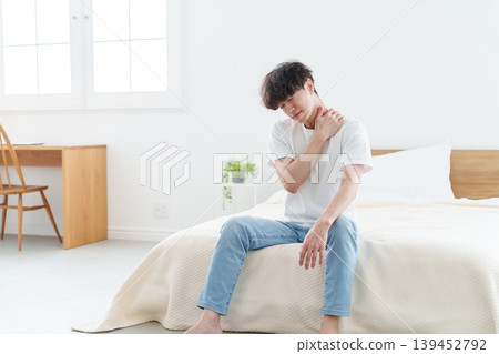 A man sitting on a bed, feeling unwell. 139452792
