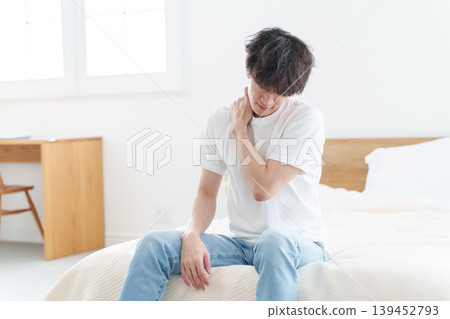 A man sitting on a bed, feeling unwell. A man sitting on a bed, feeling unwell. 139452793