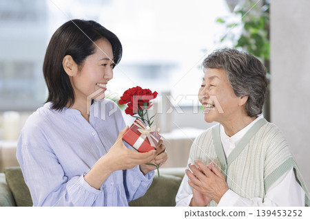 母親節圖片:一位中年女兒送給年邁的母親一份禮物。 母親節圖片:一位中年女兒送給年邁的母親一份禮物。 139453252