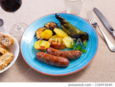 Grilled sausages served with baked potato, pepper and eggplant Grilled sausages served with baked potato, pepper and eggplant 139453640