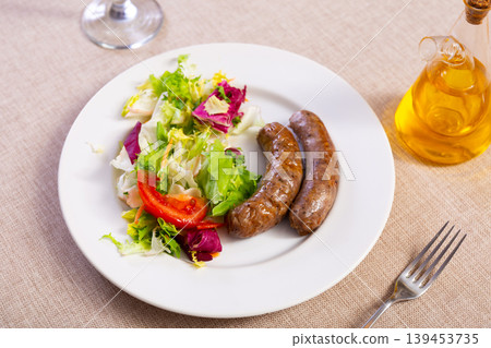 Fried sausages served with fresh vegetable salad 139453735