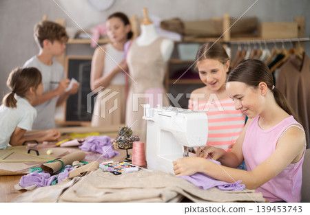 Girl child watches female classmates sew and creating clothes Girl child watches female classmates sew and creating clothes 139453743