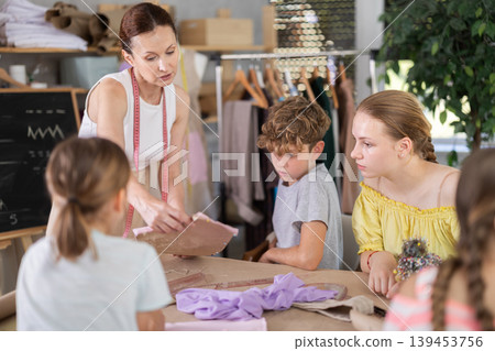 Teacher showing kids pattern work in school sewing class Teacher showing kids pattern work in school sewing class 139453756