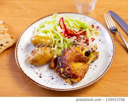 Fried chicken thigh garnished with salad of fresh vegetables and potatoes Fried chicken thigh garnished with salad of fresh vegetables and potatoes 139453786