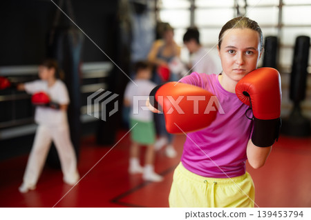 Girl posing during training in boxing gloves Girl posing during training in boxing gloves 139453794