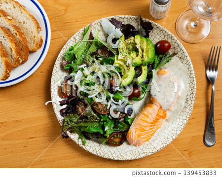 Colorful vegetable salad and grilled salmon on beige background of wooden table or tablecloth 139453833