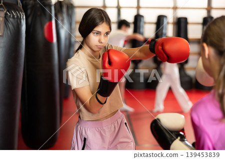 Teen girls fight with feet and hands, using all strength, courage. Kickboxing and boxing lesson 139453839