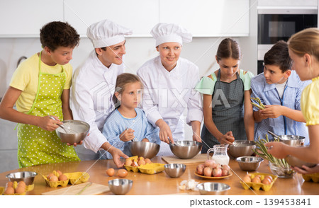 Positive professional chefs in white uniform conducting culinary masterclass for tweens 139453841