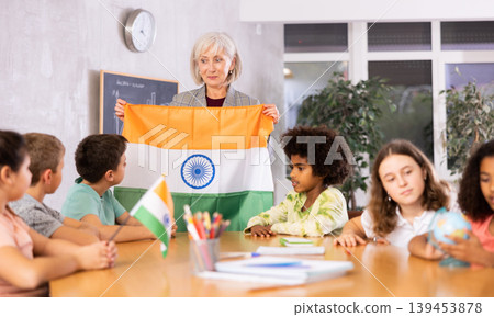 Female teacher showing indian flag to kids in geography class Female teacher showing indian flag to kids in geography class 139453878