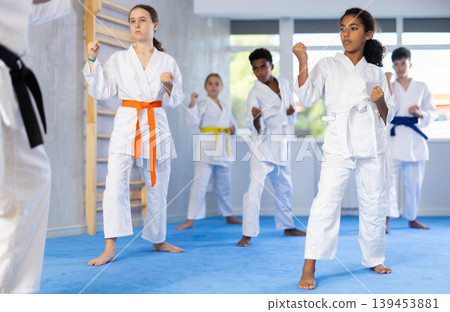 Children of different nationalities in kimono standing in fight stance during group karate training in gym Children of different nationalities in kimono standing in fight stance during group karate training in gym 139453881