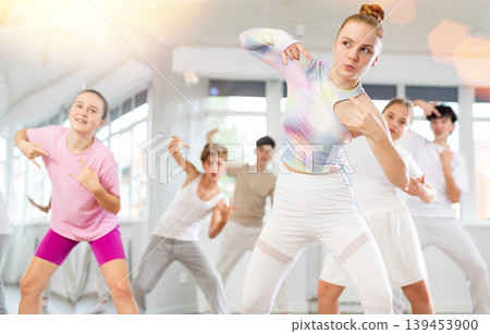 Team of teenagers rehearsing modern dances in dance hall Team of teenagers rehearsing modern dances in dance hall 139453900