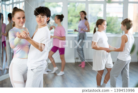 Group of positive teenagers learning to dance tango in dance studio Group of positive teenagers learning to dance tango in dance studio 139453996