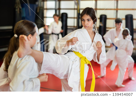 Teenage girls in white kimono at karate lesson Teenage girls in white kimono at karate lesson 139454007