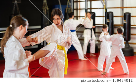 Teen girls athletes in pair conduct training battle in oriental fighting technique Teen girls athletes in pair conduct training battle in oriental fighting technique 139454011