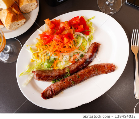 Fried sausages served with fresh vegetable salad Fried sausages served with fresh vegetable salad 139454032