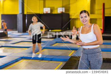Smiling female instructor inviting to jumping in trampoline arena Smiling female instructor inviting to jumping in trampoline arena 139454041