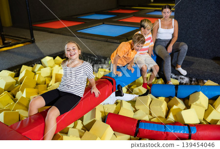 Playful happy children friends spending time together infront of foam rubber pit in trampoline game center Playful happy children friends spending time together infront of foam rubber pit in trampoline game center 139454046