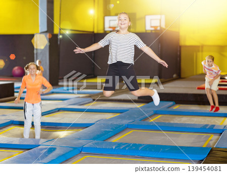 Preteen girl jumping on trampoline on indoor inflatable playground Preteen girl jumping on trampoline on indoor inflatable playground 139454081