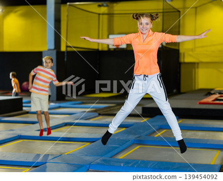 Teen girl jumping on trampoline on indoor inflatable playground Teen girl jumping on trampoline on indoor inflatable playground 139454092