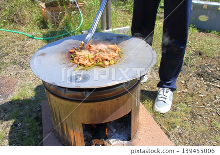 他們正享受著戶外烹飪的樂趣,使用的簡易爐灶和烤盤是由不銹鋼洗衣機內筒和改裝過的滾筒蓋製成的。 他們正享受著戶外烹飪的樂趣,使用的簡易爐灶和烤盤是由不銹鋼洗衣機內筒和改裝過的滾筒蓋製成的。 139455006