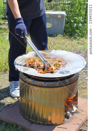They are enjoying outdoor cooking using a makeshift stove and griddle made from a stainless steel washing machine tub and a modified drum lid. They are enjoying outdoor cooking using a makeshift stove and griddle made from a stainless steel washing machine tub and a modified drum lid. 139455011