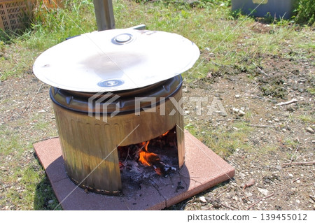 They are enjoying outdoor cooking using a makeshift stove and griddle made from a stainless steel washing machine tub and a modified drum lid. They are enjoying outdoor cooking using a makeshift stove and griddle made from a stainless steel washing machine tub and a modified drum lid. 139455012
