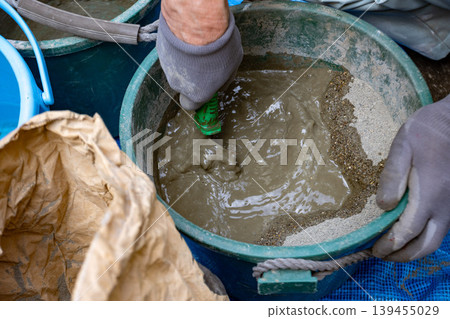 Manual work at a construction site mixing mortar Manual work at a construction site mixing mortar 139455029