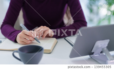 businesswoman writing notebook using tablet device hybrid work from home office setup remote worker planning tasks take notes digital workspace modern businesswoman writing notebook using tablet device hybrid work from home office setup remote worker planning tasks take notes digital workspace modern 139455305