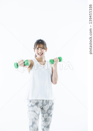 年輕女子運動服看著相機啞鈴拳 年輕女子運動服看著相機啞鈴拳 139455386