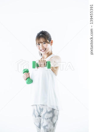 年輕女子運動服看著相機啞鈴拳 年輕女子運動服看著相機啞鈴拳 139455391