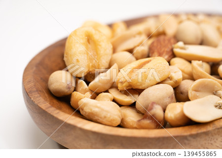 Close-up image of nuts on a wooden plate, photographed against a white background. Close-up image of nuts on a wooden plate, photographed against a white background. 139455865