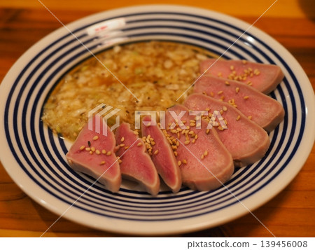 A superb snack from an izakaya: thick-cut beef tongue sashimi-style, cooked at a low temperature with green onion and salt sauce. A superb snack from an izakaya: thick-cut beef tongue sashimi-style, cooked at a low temperature with green onion and salt sauce. 139456008