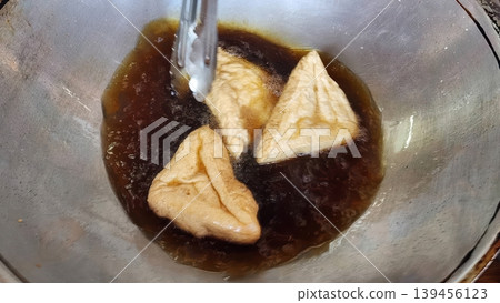 Deep Frying Triangular Tofu Puffs in a Metal Wok for Traditional Asian Cuisine Deep Frying Triangular Tofu Puffs in a Metal Wok for Traditional Asian Cuisine 139456123